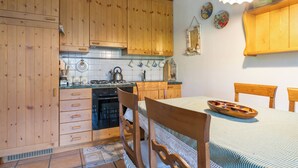 Una cocina con armarios de madera, una estufa y una mesa de comedor con sillas.