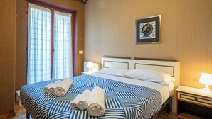 A hotel room with a large bed, two bedside lamps, a framed picture on the wall, and a window with curtains. - Maggio - appartamento con piscina (Cremeno)