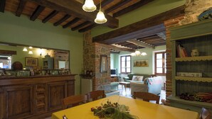 A rustic dining area with a stone fireplace, wooden beams, and a yellow table with chairs.