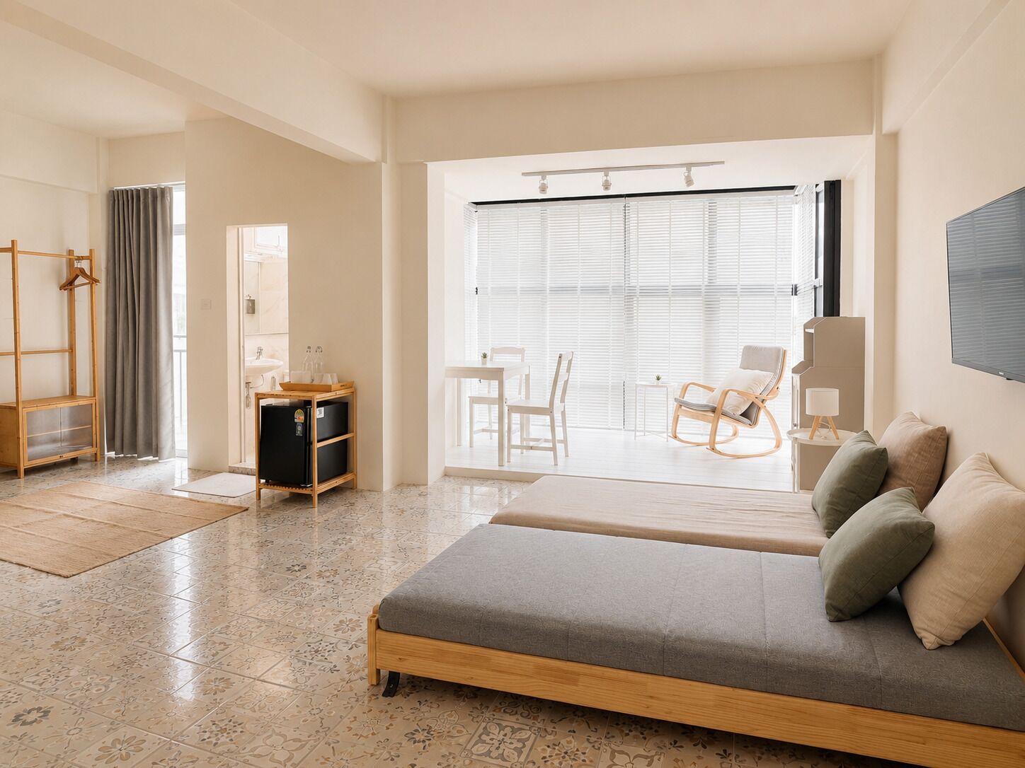 Una sala moderna con sofá, una mesa de comedor y una silla. Hay una pequeña área de cocina con refrigerador y un gabinete de madera.