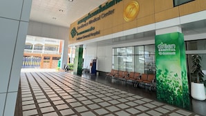 Entrada de un hospital con un cartel de la Comisión Nacional de Calidad y un letrero verde del hospital.