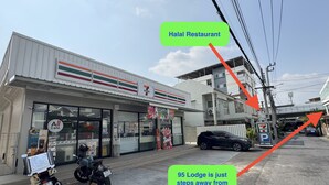 Una tienda de conveniencia 7-Eleven con un letrero de restaurante halal y un letrero de Lodge 95 que indica cercanía.