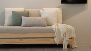 A modern living room with a sofa, pillows, a blanket, and a flat-screen TV mounted on the wall. - 95 Lodge (Wang Thonglang)