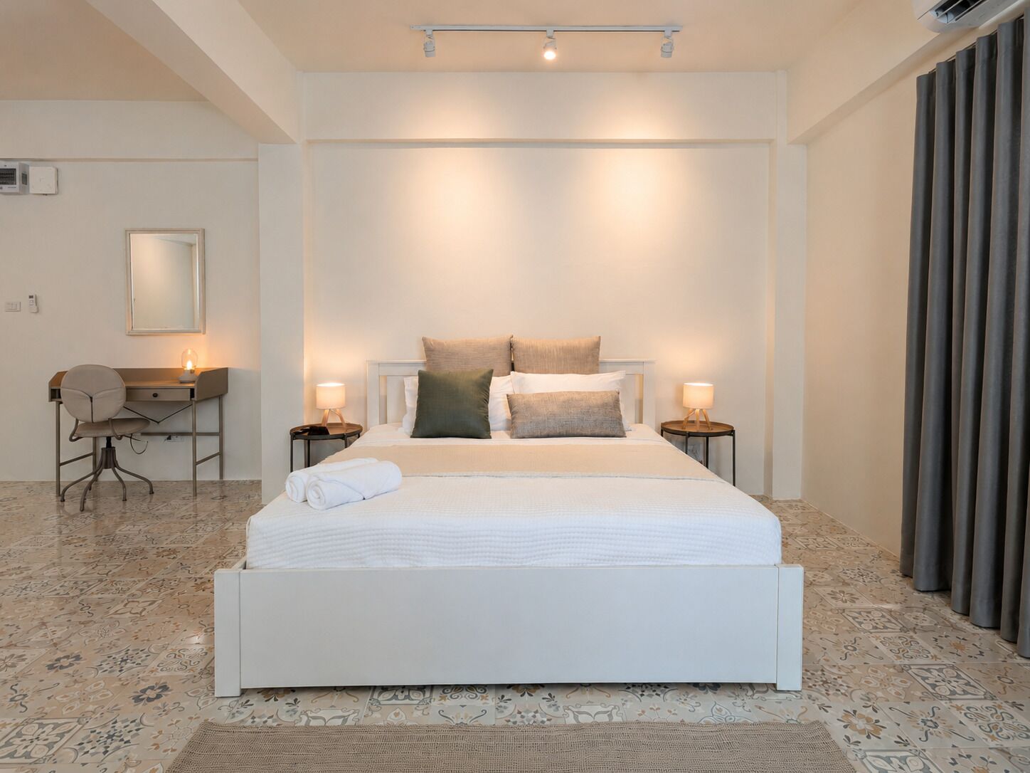 Een moderne slaapkamer met een groot bed, bedlampen, een bureau en een stoel.