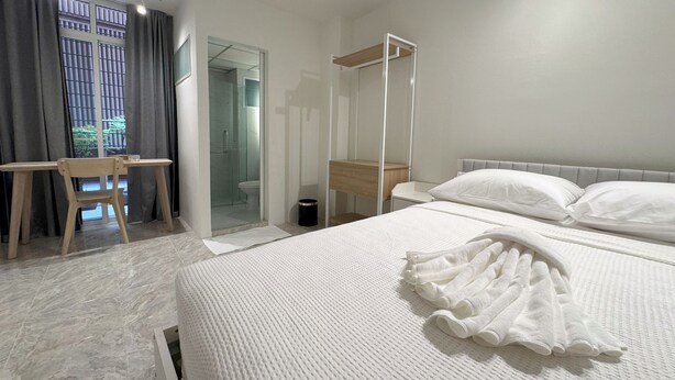 Habitación de hotel con cama, escritorio y zona de ducha.