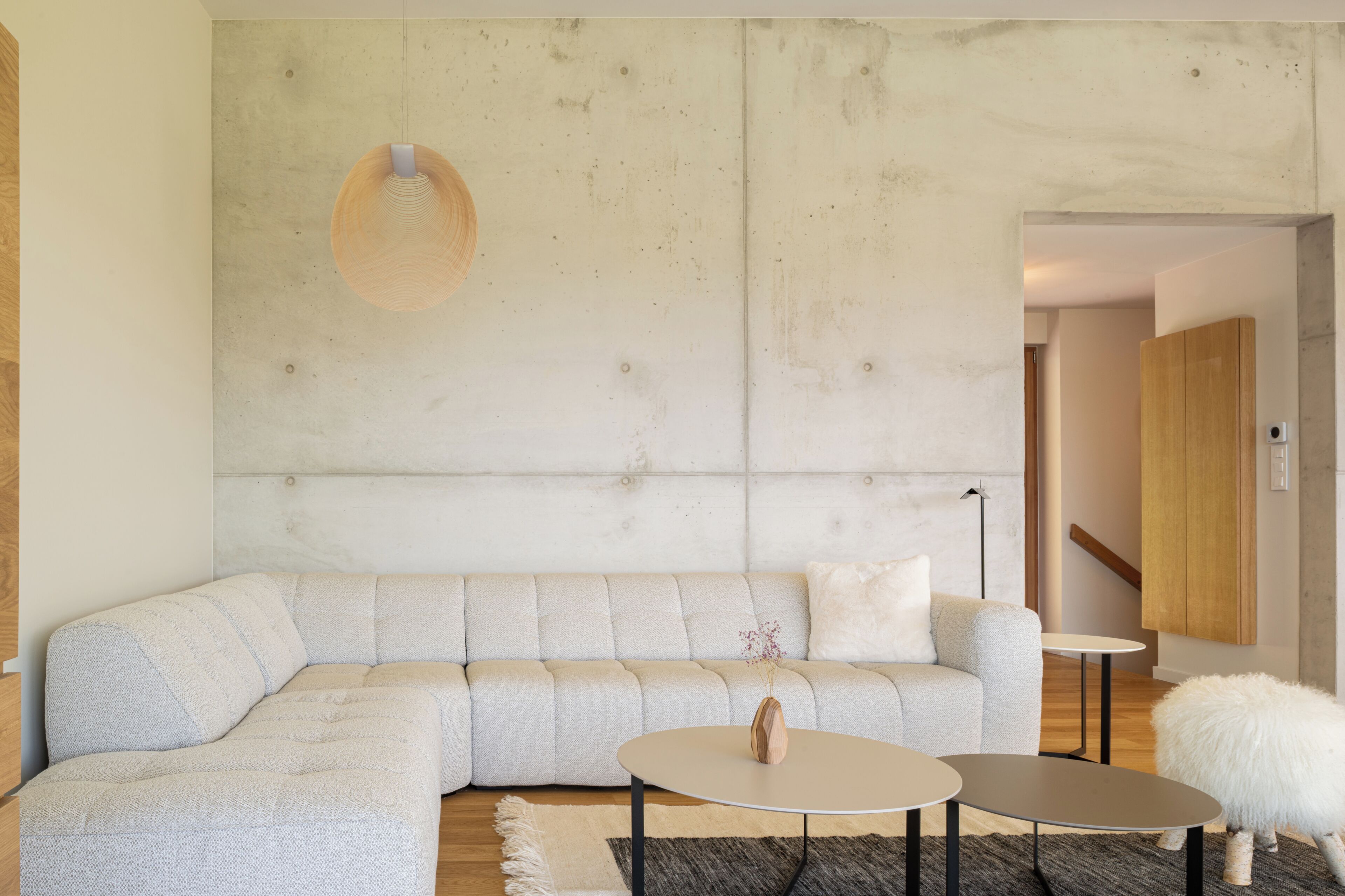 Un salon moderne avec un canapé d’angle, une table basse ronde et une petite table d’appoint.