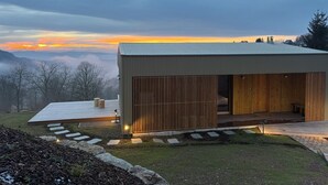 Un edificio moderno con tetto piatto, ampie porte scorrevoli in legno e un patio lastricato.