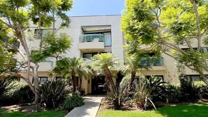 A modern building with a central entrance, surrounded by lush greenery and palm trees. - Serenity Retreat in Santa Monica (Santa Monica)