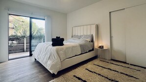 A modern bedroom with a large bed, a small bedside table, and a sliding glass door leading to an outdoor area. - Serenity Retreat in Santa Monica (Santa Monica)