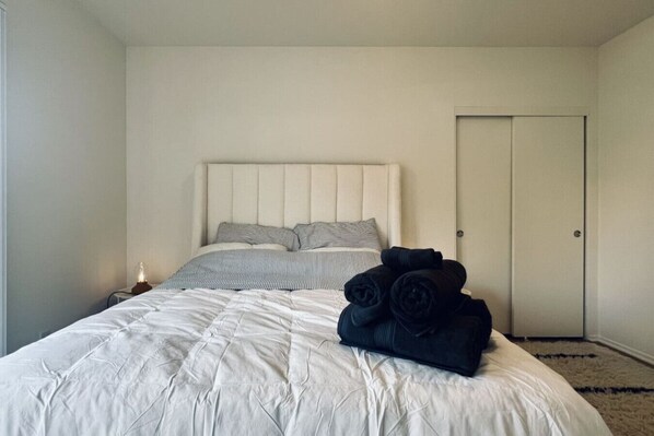 Un dormitorio con cama, mesita de noche y puerta.