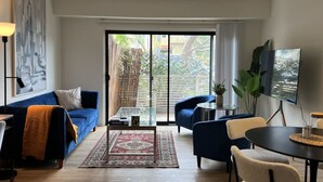 A modern living room with a blue sofa, a coffee table, and a TV on a stand. - Serenity Retreat in Santa Monica (Santa Monica)