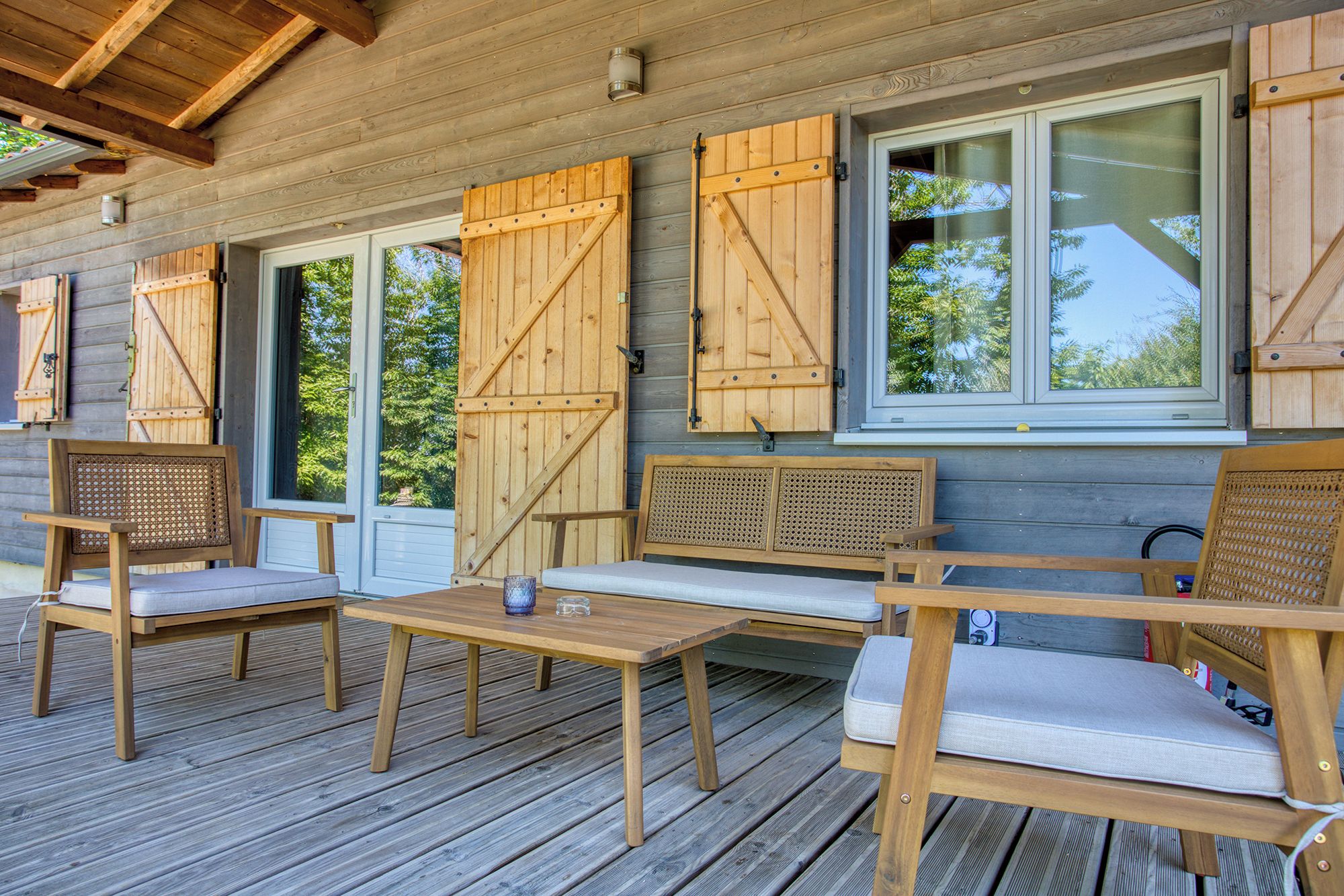 Une terrasse en bois avec des sièges extérieurs et de grandes fenêtres.