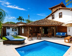 A residential property with a swimming pool, outdoor furniture, and a patio area. - Bz34 Casa 150m da praia Piscina e Sauna (Buzios)
