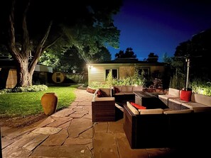 Ein Terrassenbereich im Freien mit Steinböden, Korbmöbeln und einem großen Pflanzgefäß.