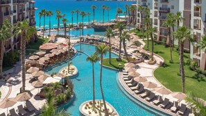 Ein Resort mit mehreren Schwimmpools, Palmen und Liegestühlen.