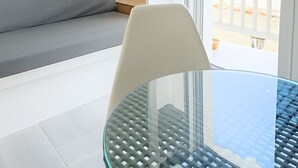 A modern room with a glass table, a grey sofa, and a balcony with a view. - Castellino Naxos (Naxos)