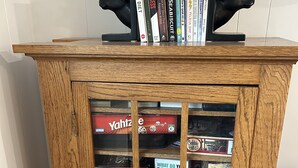 Un mueble de madera con puertas de cristal que contiene varios juegos de mesa y libros.