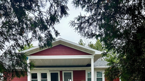 Una casa roja con un porche, un buzón y un jardín.