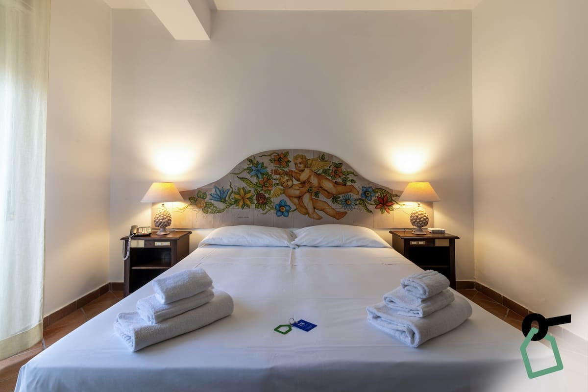 A hotel room with a large bed, two bedside lamps, and a decorative headboard.
