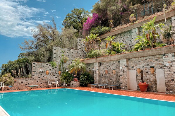 A swimming pool with stone walls and potted plants. - Hotiday Taormina Mare (Taormina)