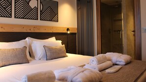 A hotel room with a neatly made bed, a set of towels, and three wall art pieces. - Les Cîmes d'Auréa (Valloire)