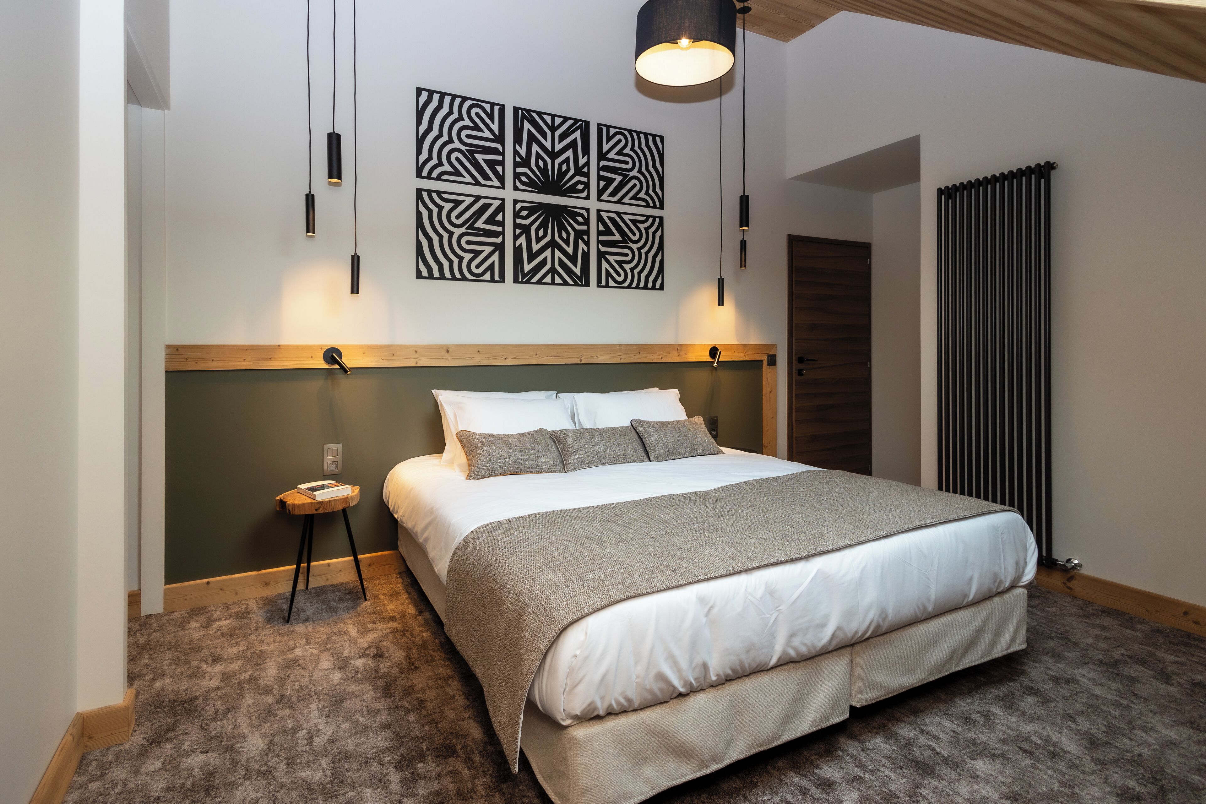 A bedroom with a large bed, a bedside table, a wall-mounted light fixture, and a radiator.