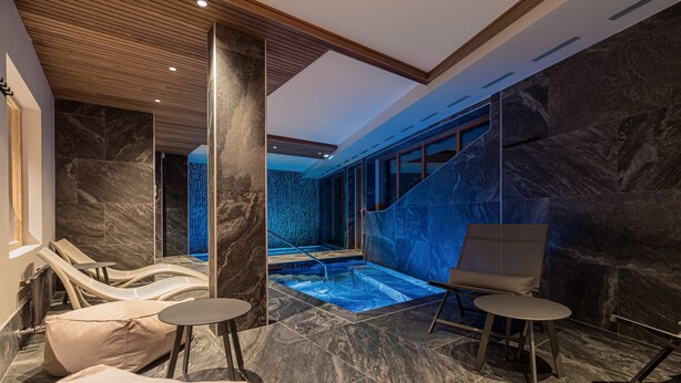 A modern spa area with a hot tub, lounge chairs, and a staircase leading to a higher level. - Les Cîmes d'Auréa (Valloire)