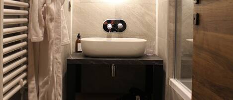 A modern bathroom with a large oval mirror, a white sink, and a towel rack.
