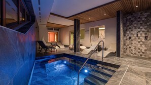 A modern indoor pool area with lounge chairs and a stone wall. - Les Cîmes d'Auréa (Valloire)
