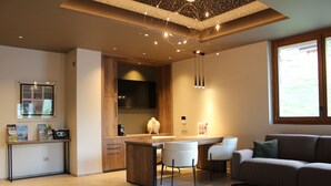 A modern kitchen with a central island, bar stools, and a built-in oven. - Les Cîmes d'Auréa (Valloire)
