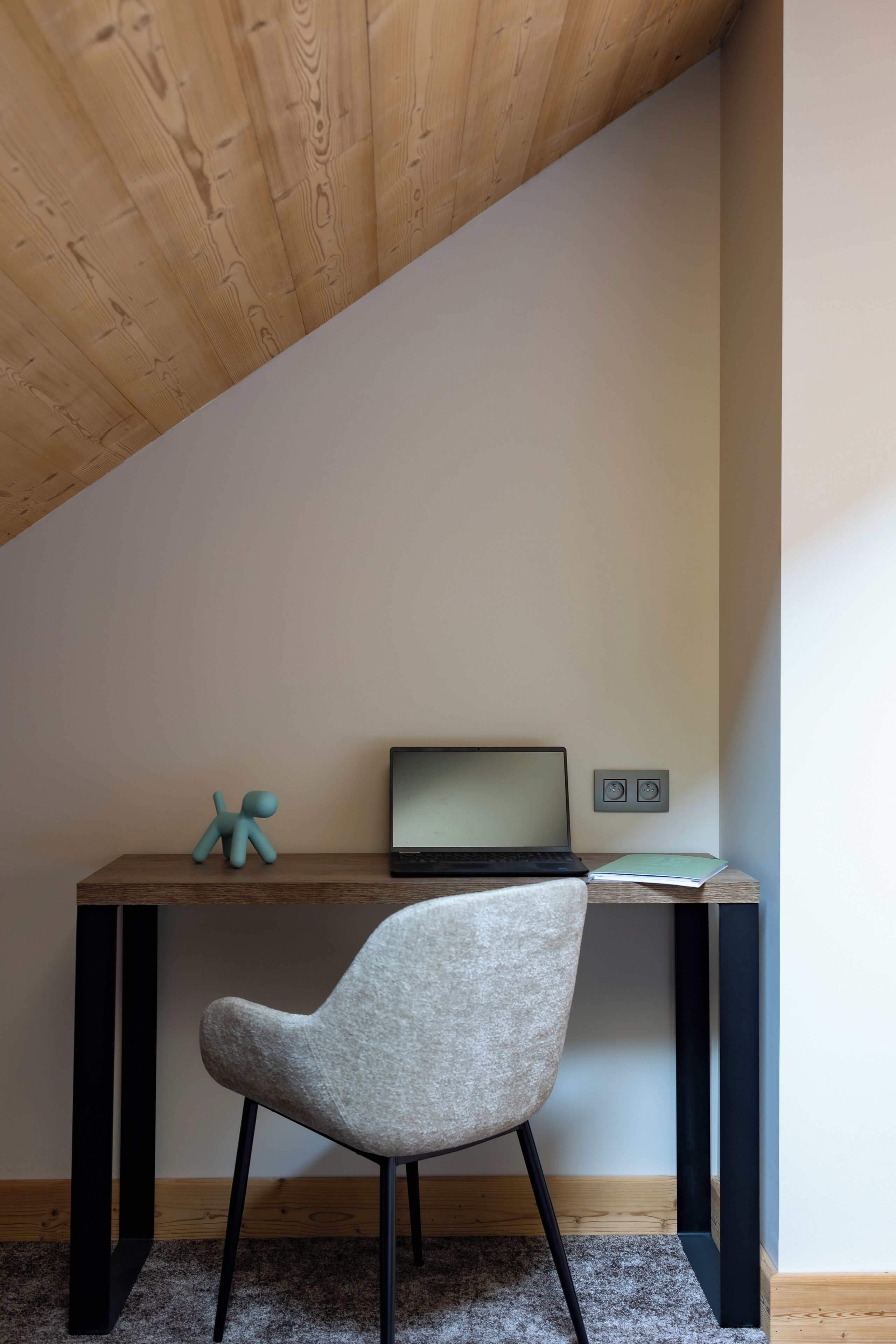 Et moderne arbejdsområde med en bærbar computer, en lille figur og en stol.