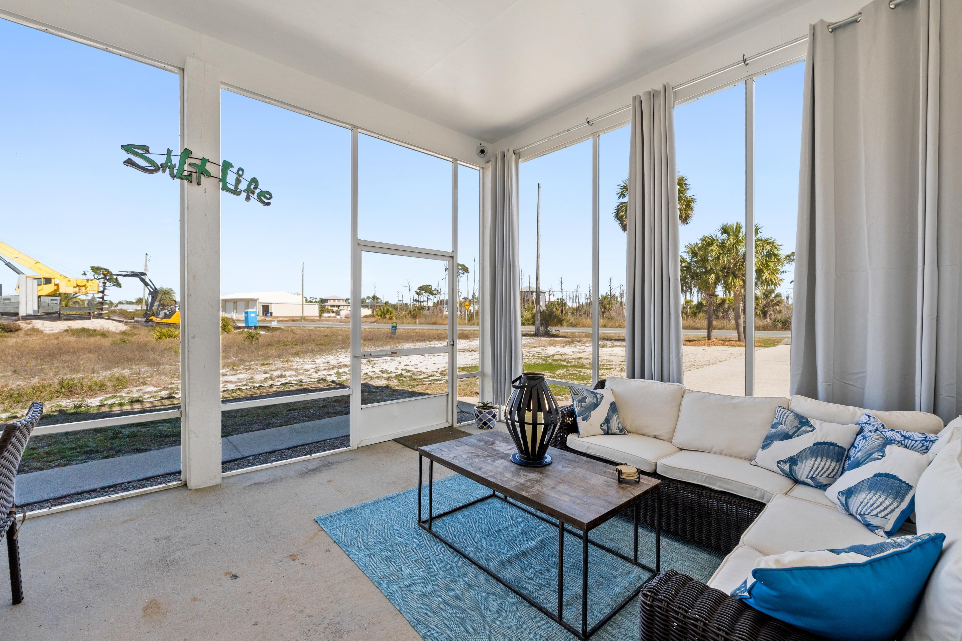 A spacious room with a large window, a white sofa, a coffee table, and a view of a construction site.