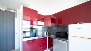 A compact kitchen with red cabinets, a microwave, a dishwasher, and a refrigerator. - Clématite - Vue mer, plage à 100m, proche Espagne (Saint-Cyprien)
