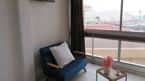 A room with a blue sofa, a small wooden table with a vase of flowers, and a TV mounted on the wall. - Clématite - Vue mer, plage à 100m, proche Espagne (Saint-Cyprien)
