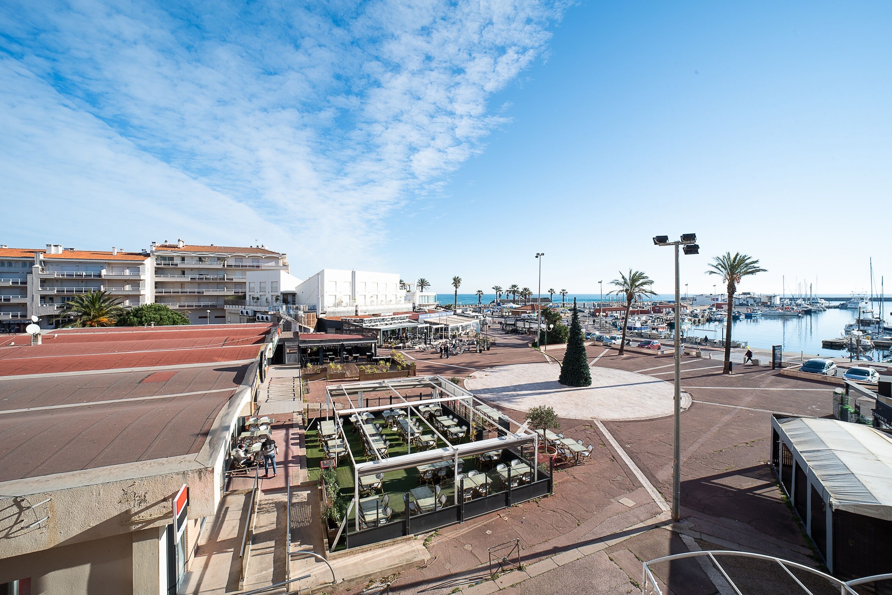 A coastal marina with a restaurant patio overlooking the water.