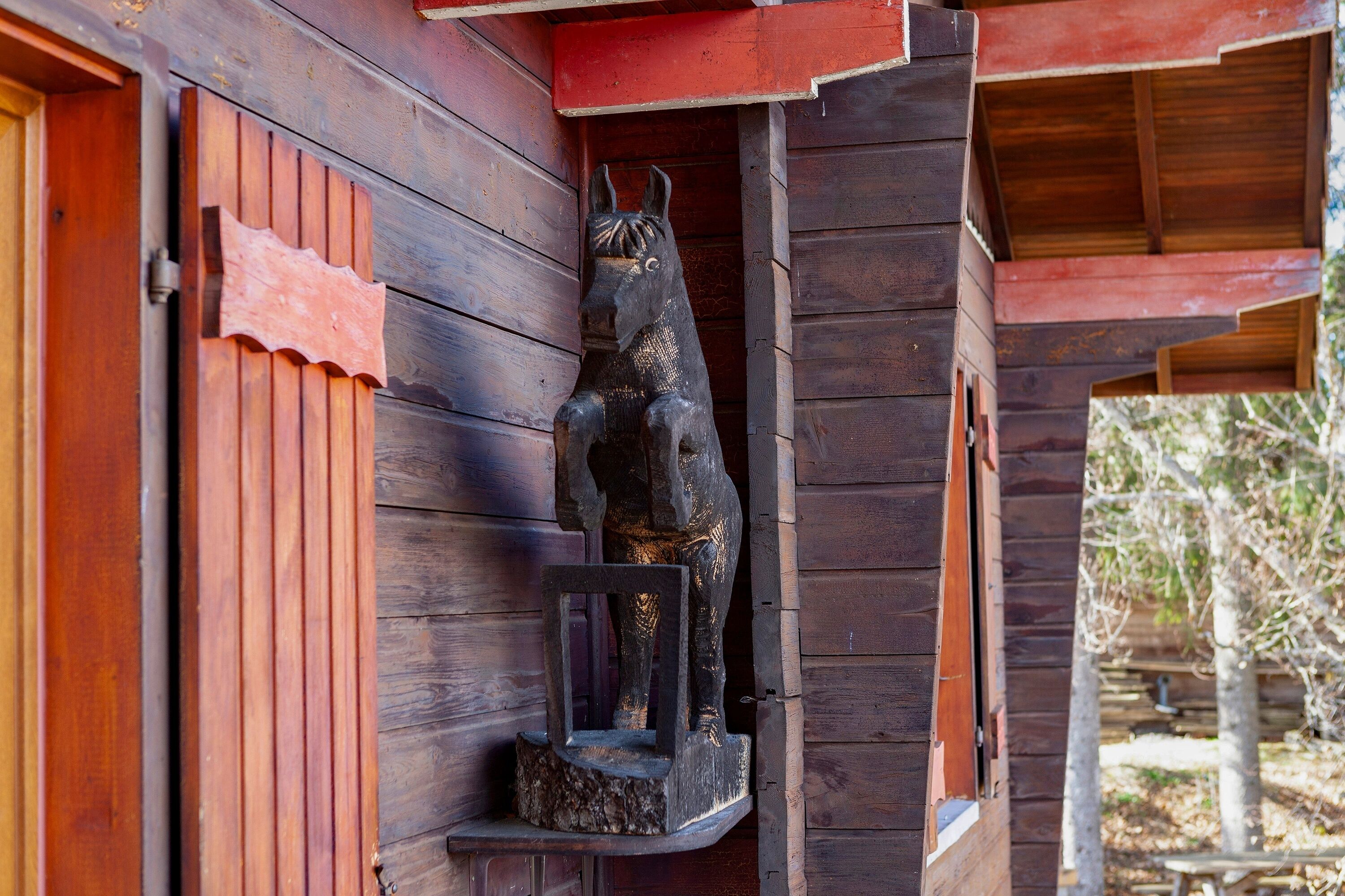 Une cabane en bois avec une sculpture de cheval sur le porche.
