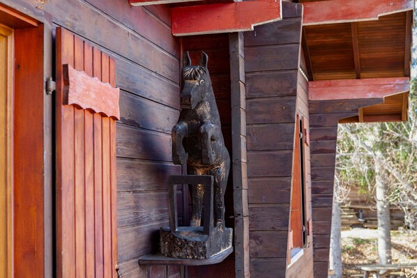 Una cabana de fusta amb una escultura de cavall al porxo.
