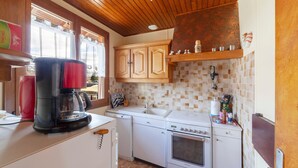 Une cuisine compacte équipée d’une machine à café, d’un lave-vaisselle et d’une cuisinière.