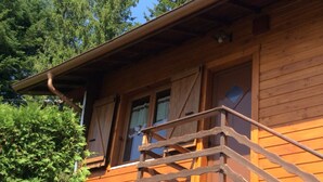 Une cabane en bois dotée d’un balcon, entourée d’arbres.