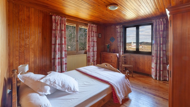 Une chambre à coucher aux murs lambriss és, avec un lit, une commode et une chaise.