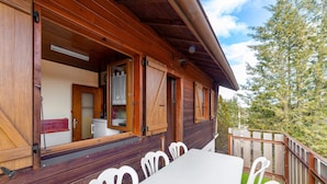 Une cabane en bois avec un coin repas et une cuisine visibles à travers la porte ouverte.
