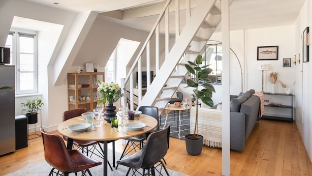 Een modern loft met een eethoek, trap en woonruimte.