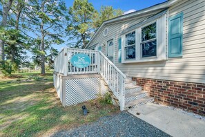 A house with a porch, a wooden staircase, and a sign that reads 'Welcome to Bayside Haven.'