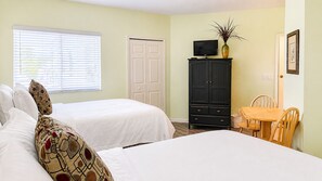 A room with two beds, a television, a cabinet, and a dining table.