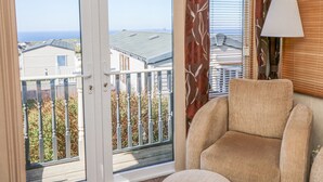 En balkong med utsikt över hus och havet, en stol och en lampa.