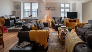A modern living room with a sofa, armchairs, a coffee table, and a television.