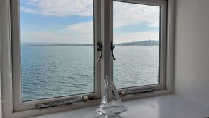 A window with a view of a calm sea and distant land.