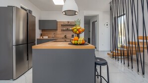 A modern kitchen with a central island, stainless steel appliances, and a fruit bowl. - Villa Merci ZadarVillas (Privlaka)