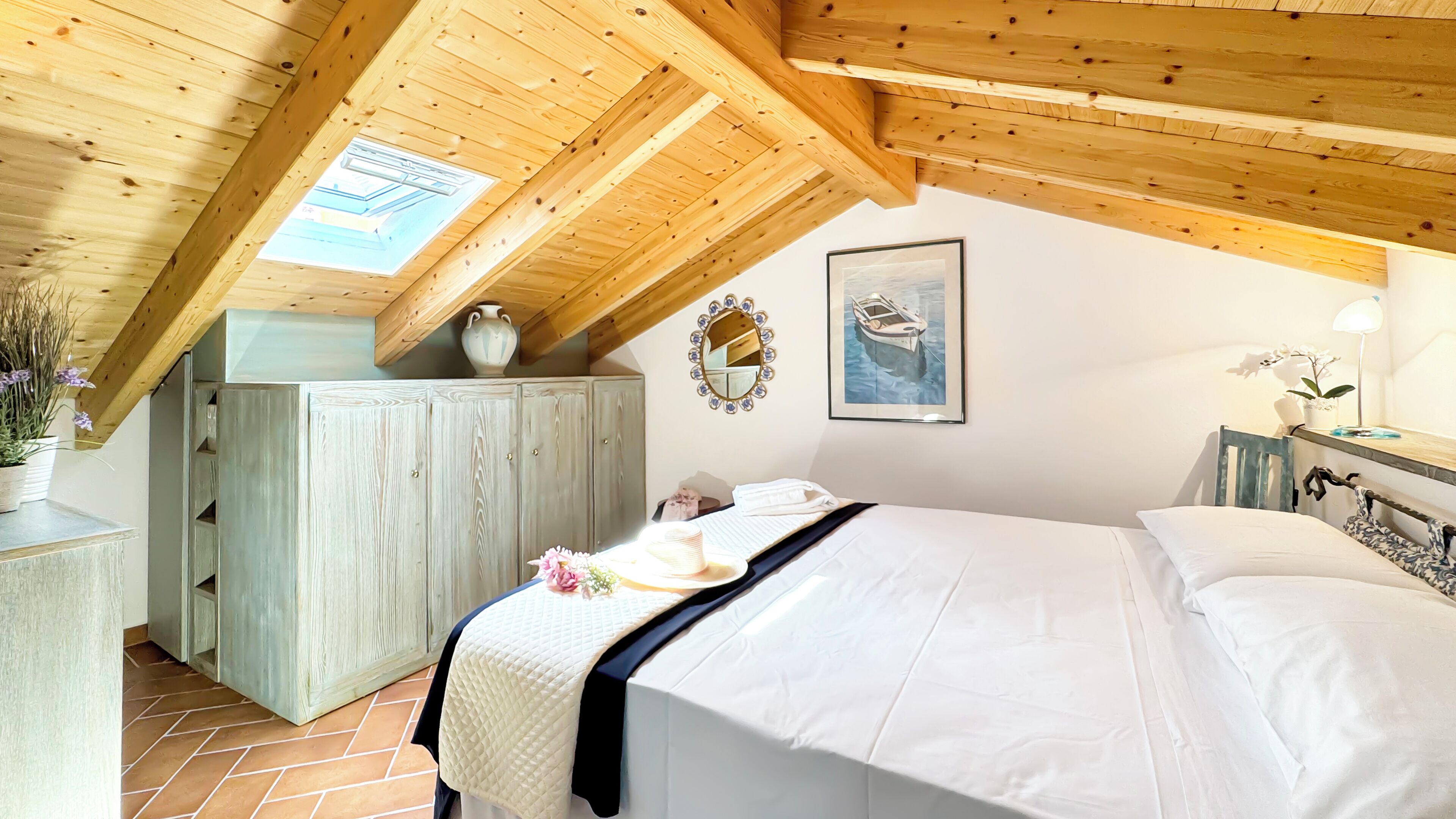 Une chambre avec un plafond en pente, un lit, un bureau et une fenêtre.