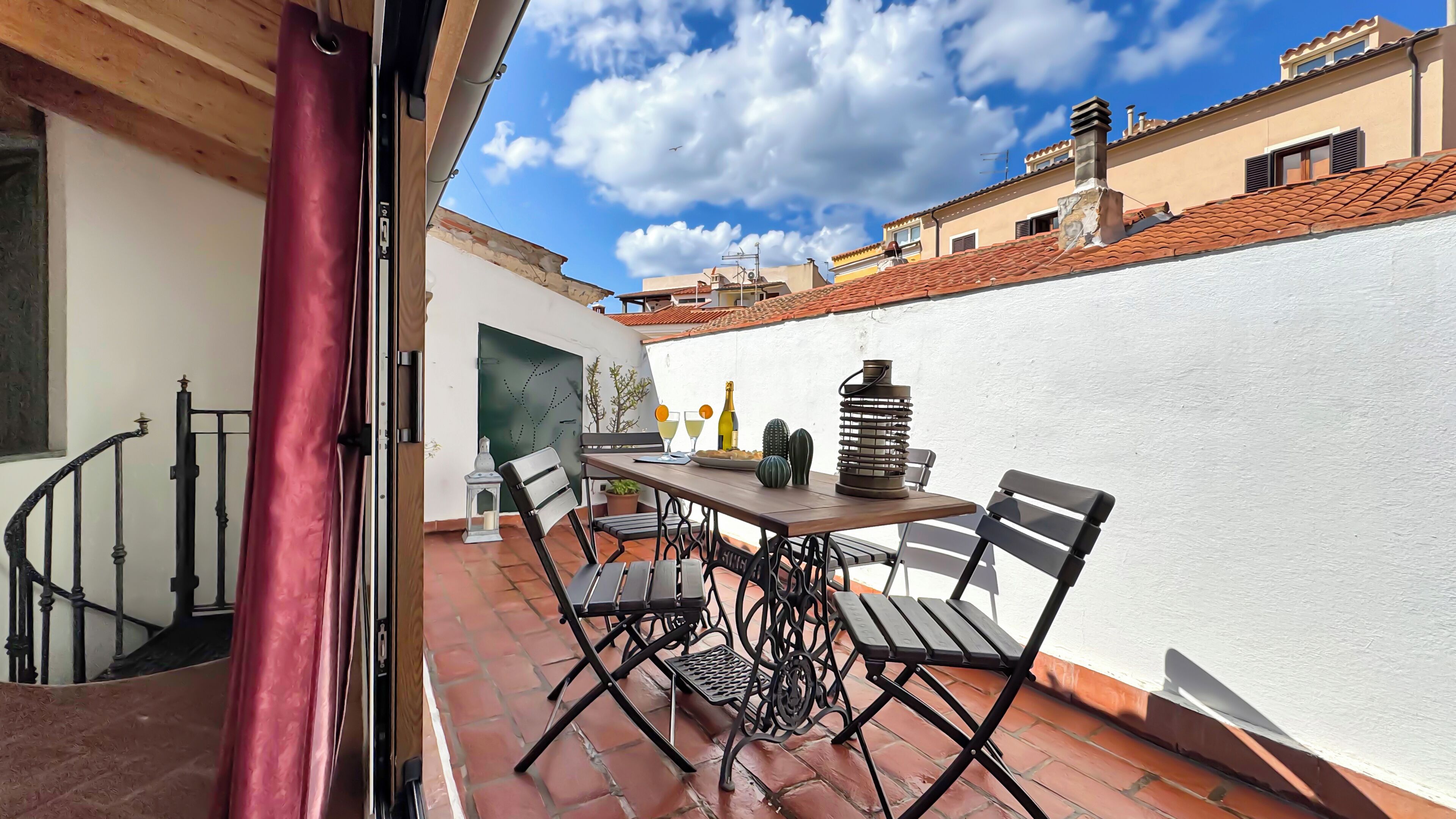 Une terrasse avec une table, des chaises et une bouteille de champagne.